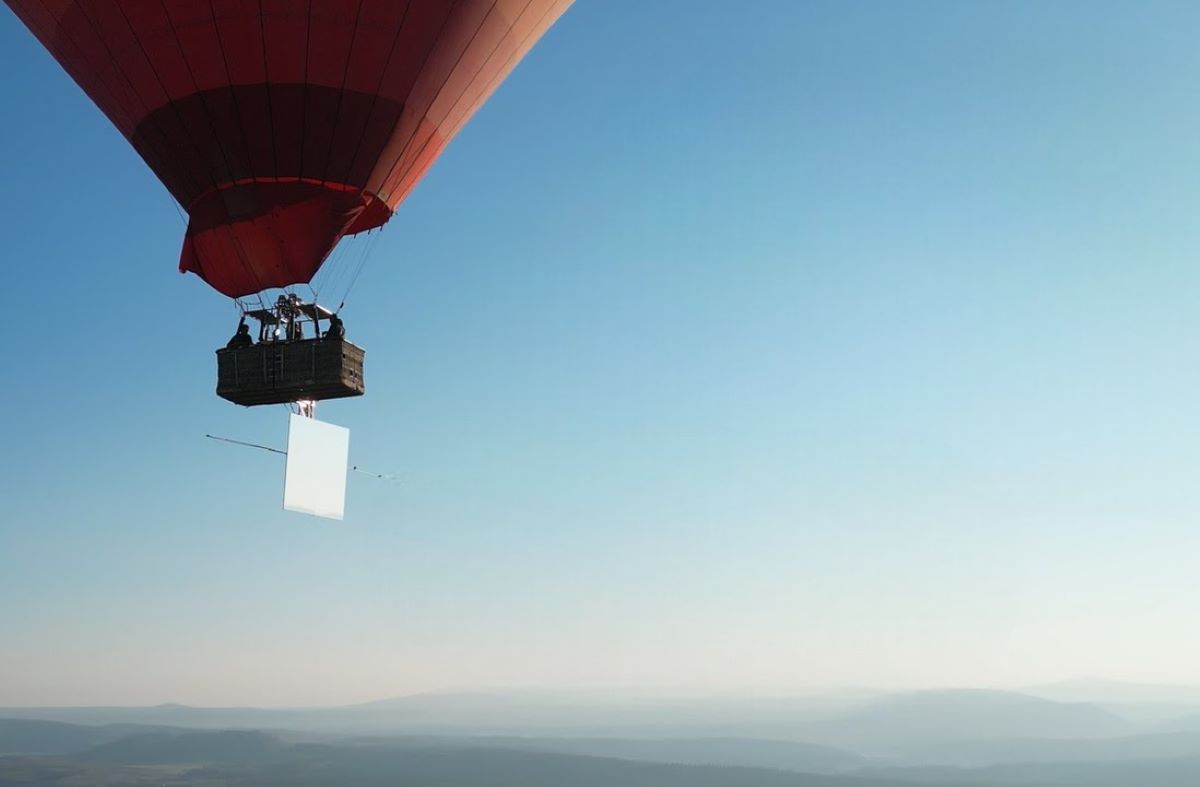 Esta imagen parece mostrar un globo aerostático con una canasta que transporta un espejo. Es posible que se trate de una prueba de Reflect Orbital, la start-up que está experimentando con el uso de espejos para reflejar la luz solar hacia áreas específicas de la Tierra, incluso durante la noche. Según lo que se sabe sobre el proyecto, este tipo de pruebas preliminares se llevan a cabo utilizando globos para simular el funcionamiento de los satélites en órbita.

El espejo suspendido bajo el globo probablemente esté diseñado para redirigir la luz solar y observar cómo afecta a los paneles solares ubicados en tierra, algo que Reflect Orbital ha realizado con éxito durante las horas diurnas. Aunque la tecnología aún está en fase de desarrollo, esta prueba refleja los esfuerzos de la empresa para evaluar la viabilidad del proyecto antes de poner en órbita los satélites planificados.

Esta imagen captura claramente una etapa importante en el desarrollo de la tecnología de Reflect Orbital, mostrando un enfoque innovador para aumentar la producción de energía fotovoltaica mediante la reflexión de la luz solar.